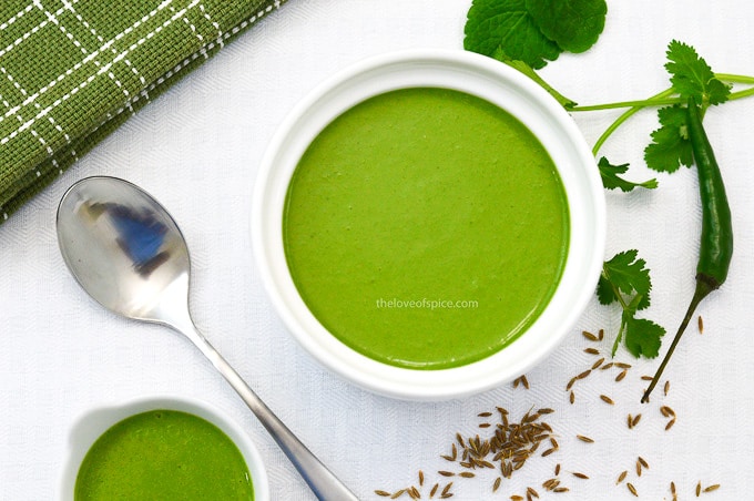 bowls of coriander mint yogurt chutney with green chili & cumin seeds on the side