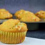 a banana white chocolate chip muffin placed in the front of a tray full of more muffins in the background