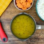 small pot of konkani daali varan, with a bowl of rice, and small bowl of crunchy vodi