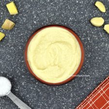 ginger garlic paste in a red bowl, along with some chunks of ginger & garlic, and some salt