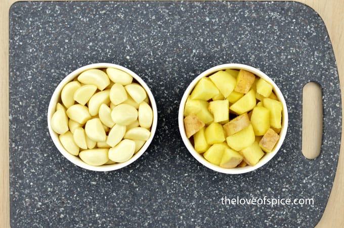 a bowl of ginger cubes and another bowl of garlic cloves