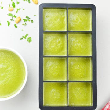 an ice cube tray full of coriander mint green chutney to be frozen, alongside a fresh bowl of green chutney