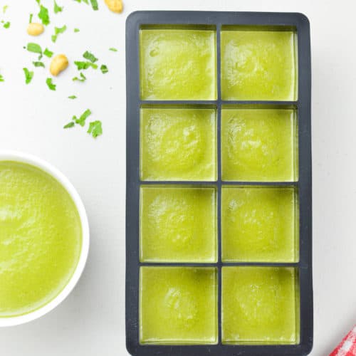 an ice cube tray full of coriander mint green chutney to be frozen, alongside a fresh bowl of green chutney