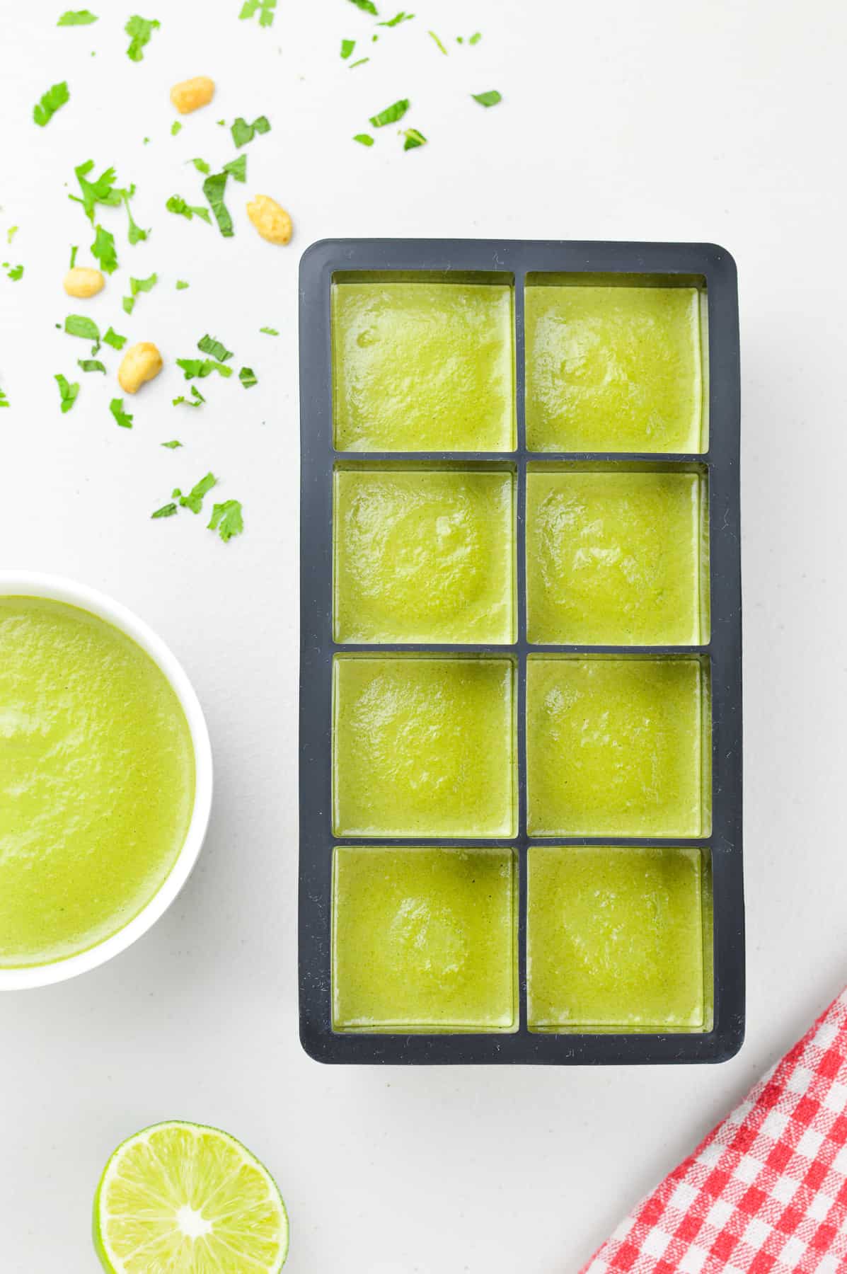 an ice cube tray full of coriander mint green chutney to be frozen, alongside a fresh bowl of green chutney