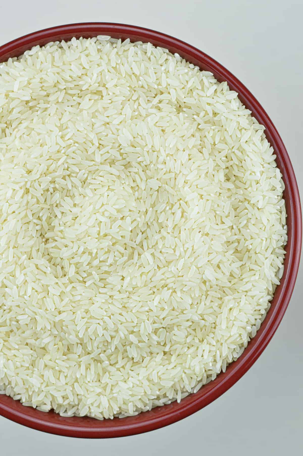 raw white sona masoori rice in a red bowl