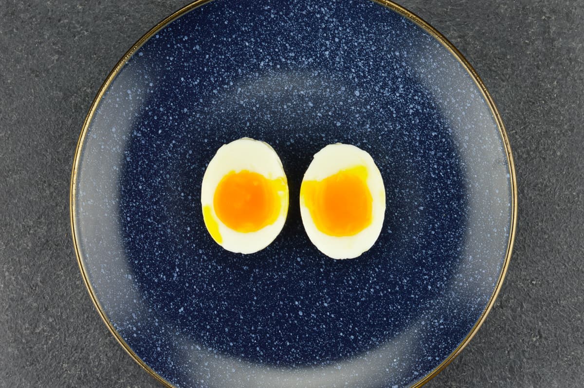 a blue plate with one soft boiled egg, which is cut open vertically into two