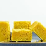 close up of 4 pieces of mysore pak placed on a blue plate