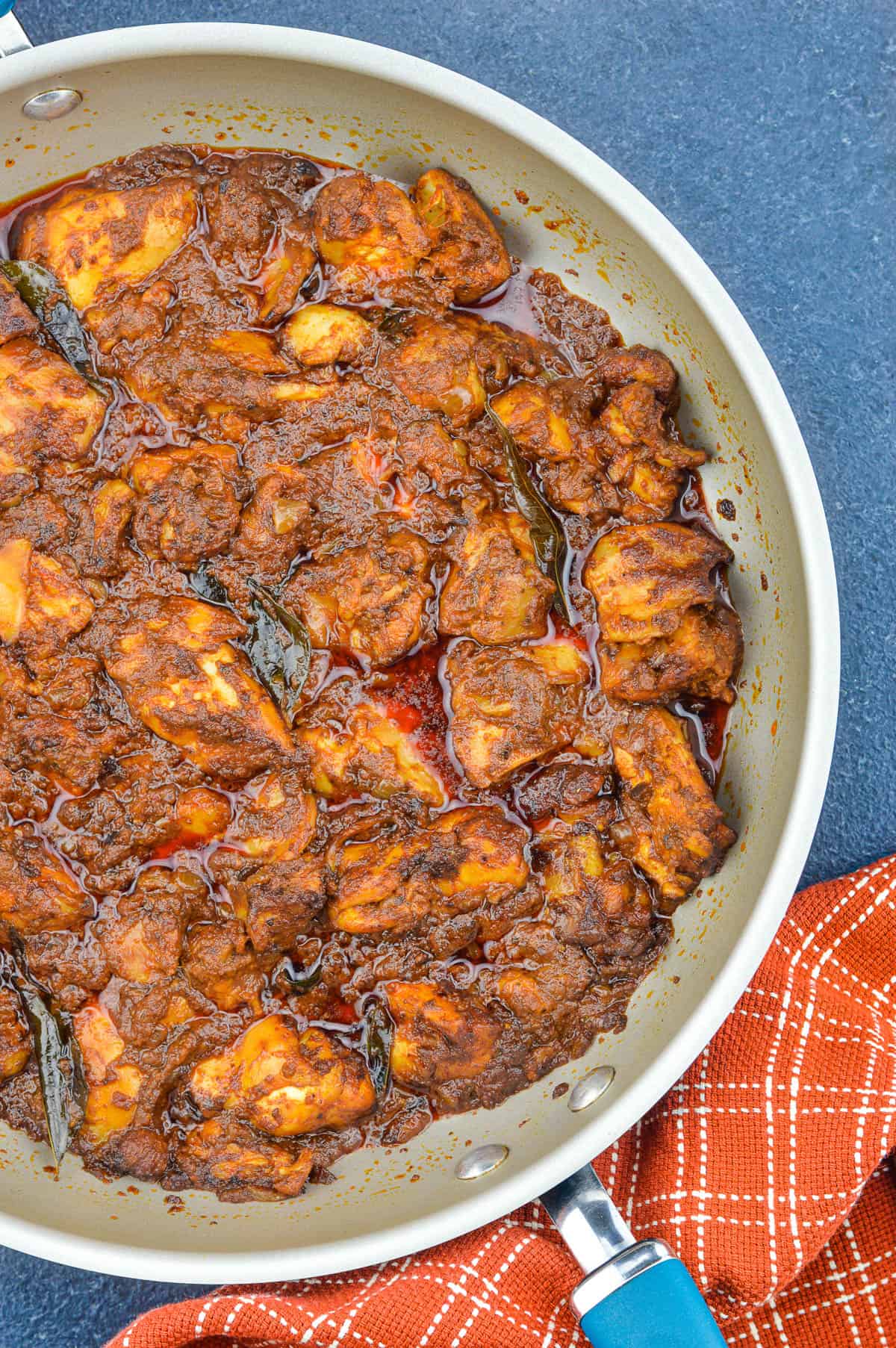 top shot of chicken ghee roast in a pan, with a kitchen towel on the side