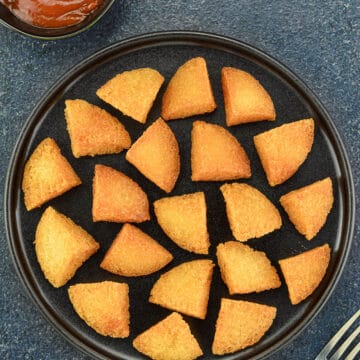 top shot of a plate of crispy deep fried idli bites, served with a schezwan chutney dip on the side