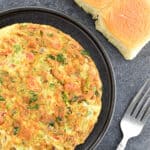 indian style masala omelette served in a plate, with 2 Indian style ladi pav on the side