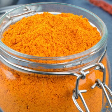 a close up shot of an open glass jar of sambar powder