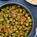 a big bowl of bhindi masala, served with rotis and yogurt on the side