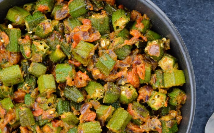 a big bowl of bhindi masala, served with rotis and yogurt on the side