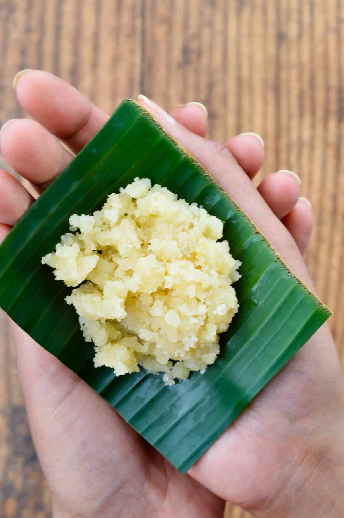 a single serving of sapaath /  satyanarayan pooja prasad, on a small piece of banana leaf, held in the palm of a hand