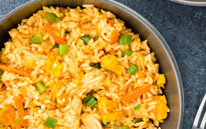 top shot of a bowl full of chicken fried rice, with chicken manchurian and schezwan chutney on the side.