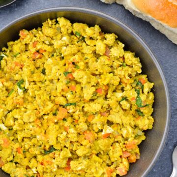 close up shot of a big bowl of egg bhurji, with 2 pav (bread) on the side.