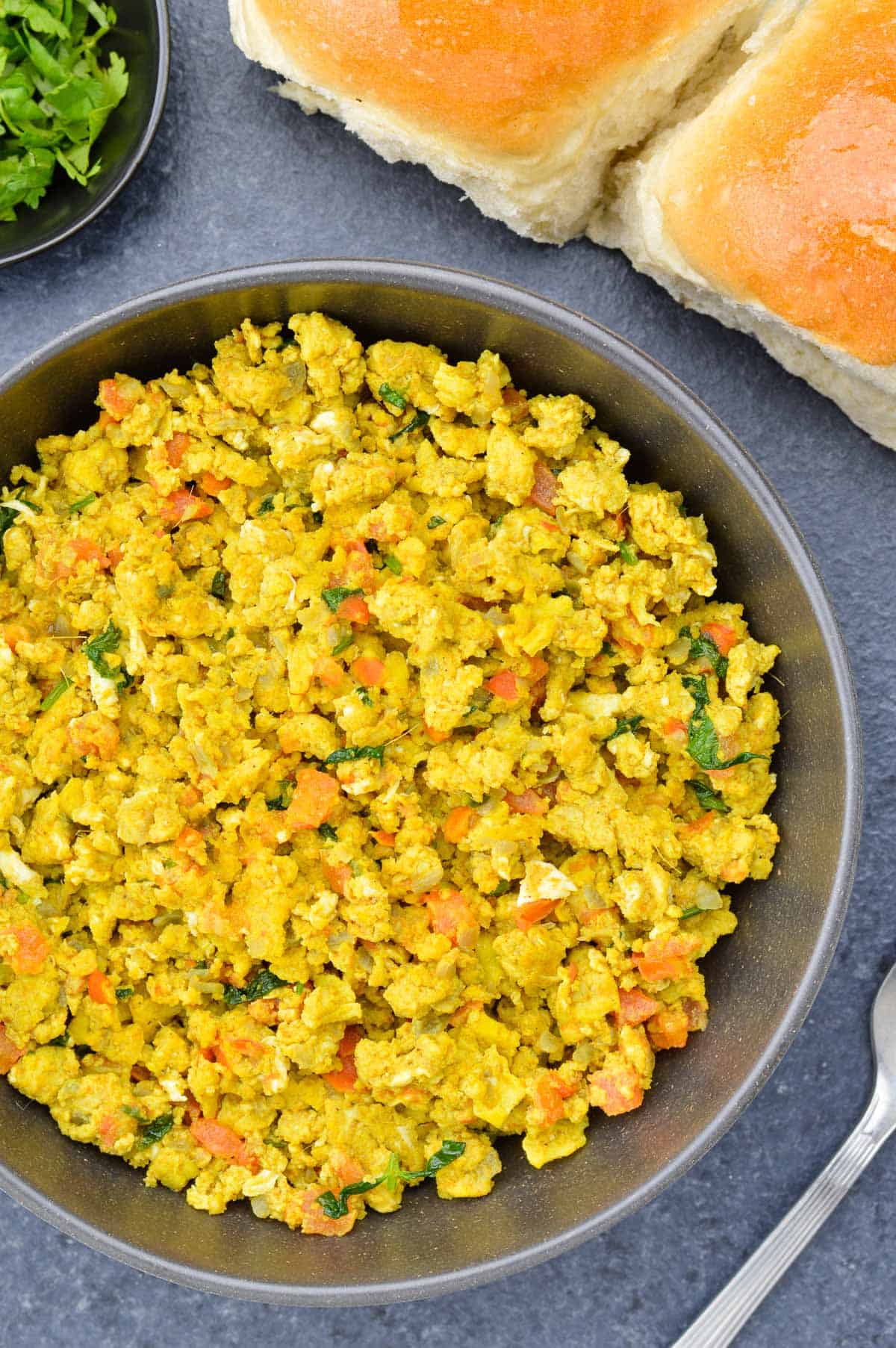 close up shot of a big bowl of egg bhurji, with 2 pav (bread) on the side.