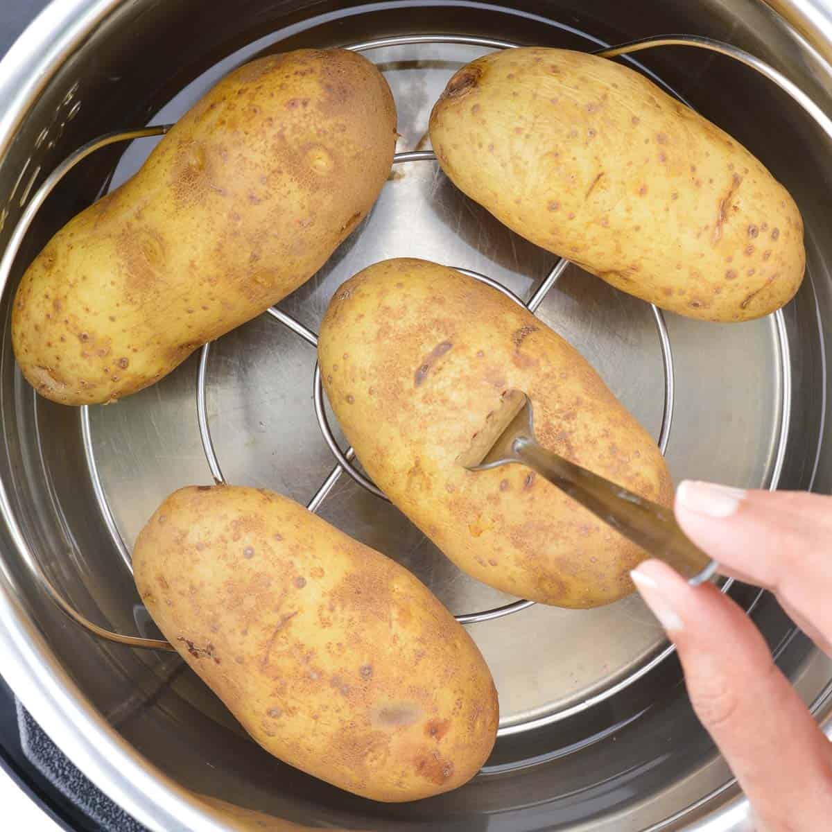 a close up of fork-tender boiled potatoes placed on a trivet inside the instant pot.