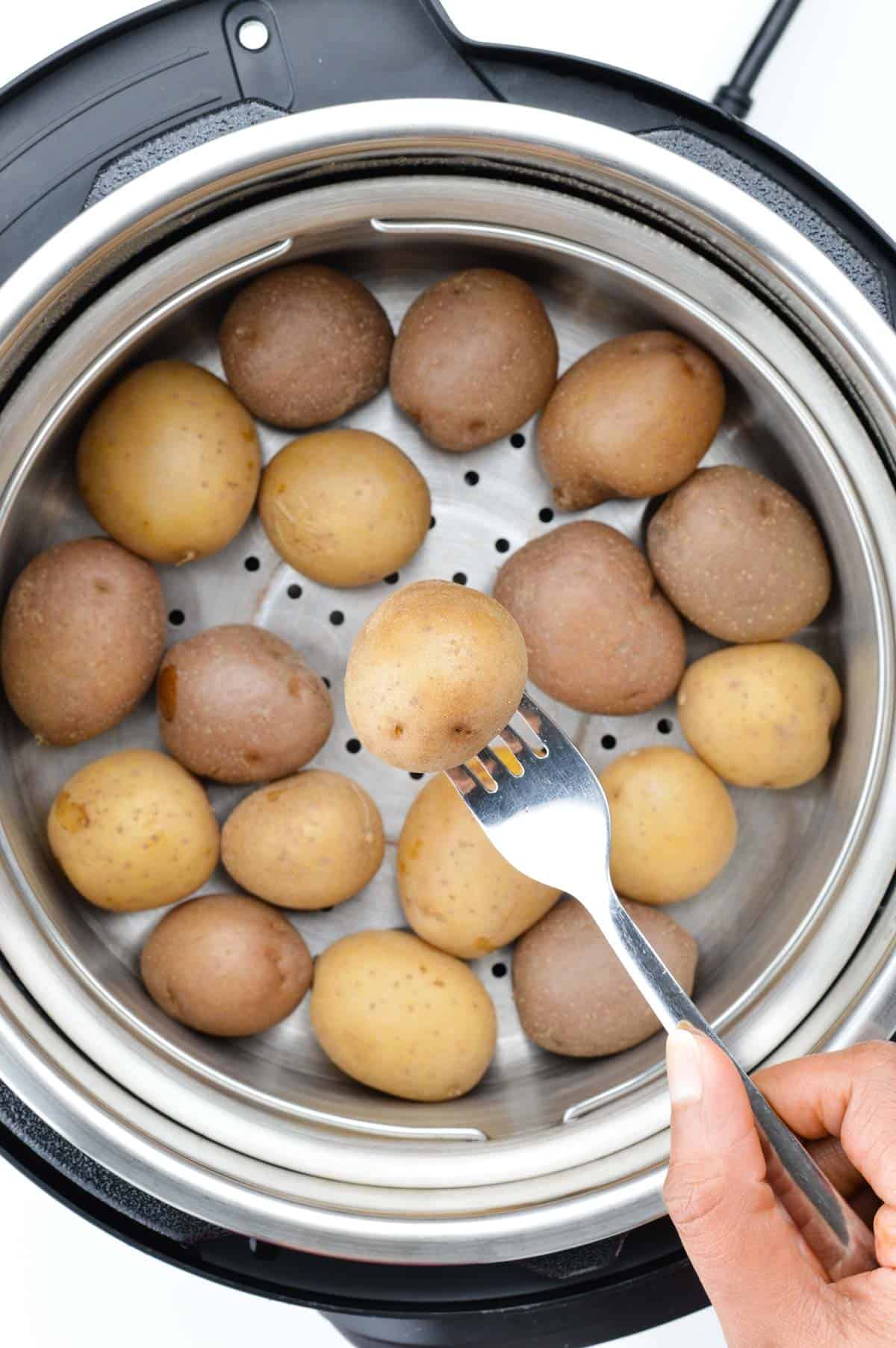 close up shot of fork-tender boiled baby potatoes in the steamer basket of the instant pot.