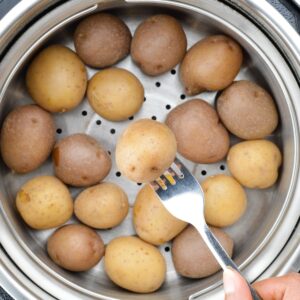 close up shot of fork-tender boiled baby potatoes in the steamer basket of the instant pot.