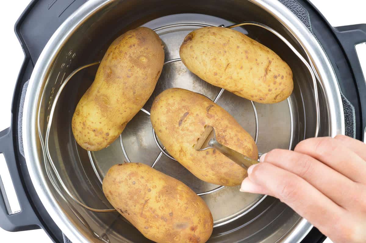 a close up of fork-tender boiled potatoes placed on a trivet inside the instant pot.